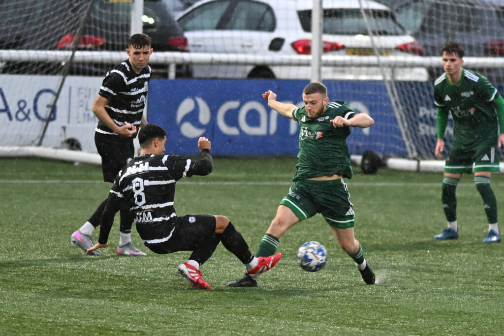 Ben Heal and an East Stirlingshire player are challenging for the ball. Rain is falling in the background.